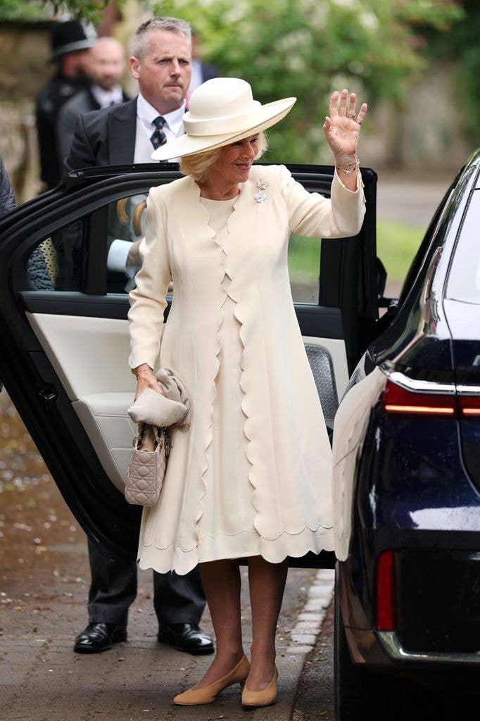 Королева Камилла машет рукой, выходя из машины Королева Камилла машет рукой, выходя из машины